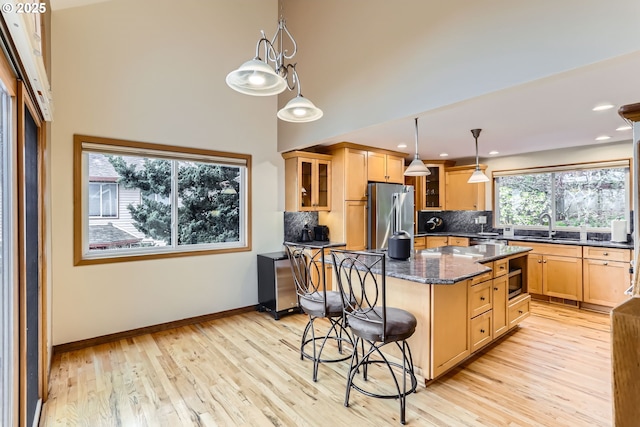 4939 Hampton Ct, Lake Oswego, OR 97035 - kitchen featuring high end fridge, a sink, a breakfast bar, decorative backsplash, and glass insert cabinets