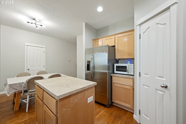 18246 SW Orlov Ct, Beaverton, OR 97078 - kitchen with stainless steel refrigerator with ice dispenser, white microwave, a kitchen island, wood finished floors, and light brown cabinetry
