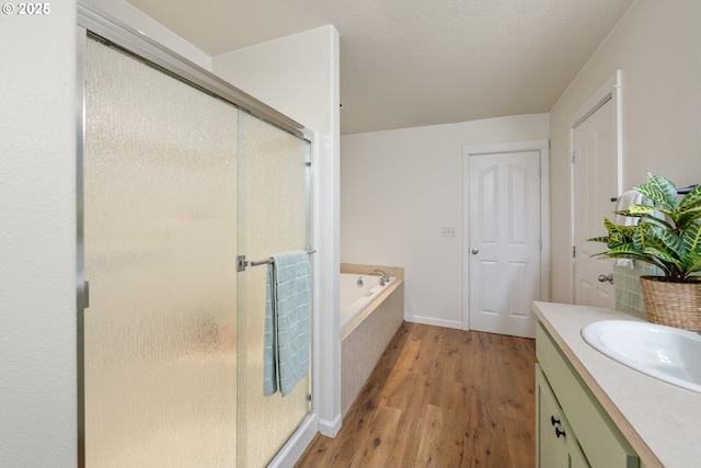 18246 SW Orlov Ct, Beaverton, OR 97078 - bathroom featuring a shower stall, wood finished floors, a bath, vanity, and baseboards