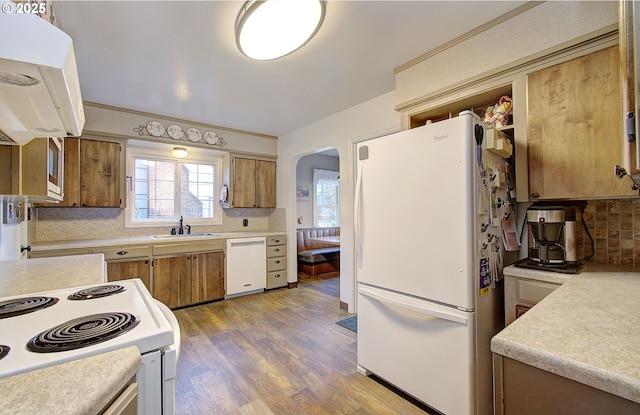 kitchen featuring sink, tasteful backsplash, extractor fan, light hardwood / wood-style floors, and white appliances