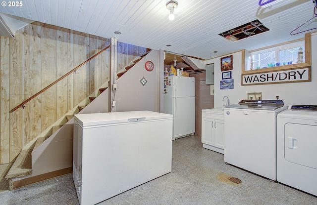 washroom with washing machine and clothes dryer, wood walls, sink, and cabinets