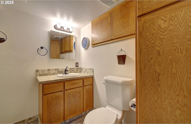 bathroom with decorative backsplash, toilet, a textured ceiling, and vanity