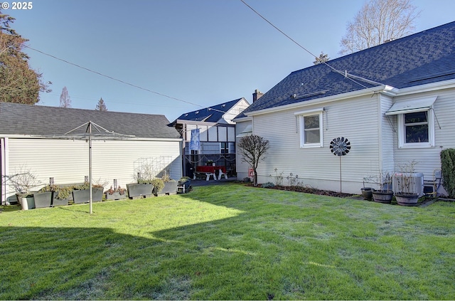 rear view of property featuring central air condition unit and a yard