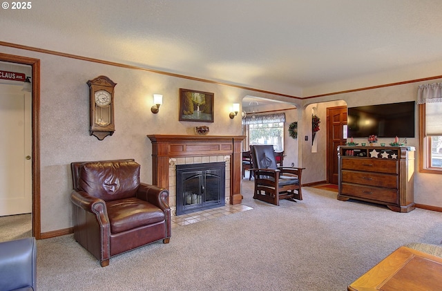 living room with light carpet, crown molding, and a tiled fireplace