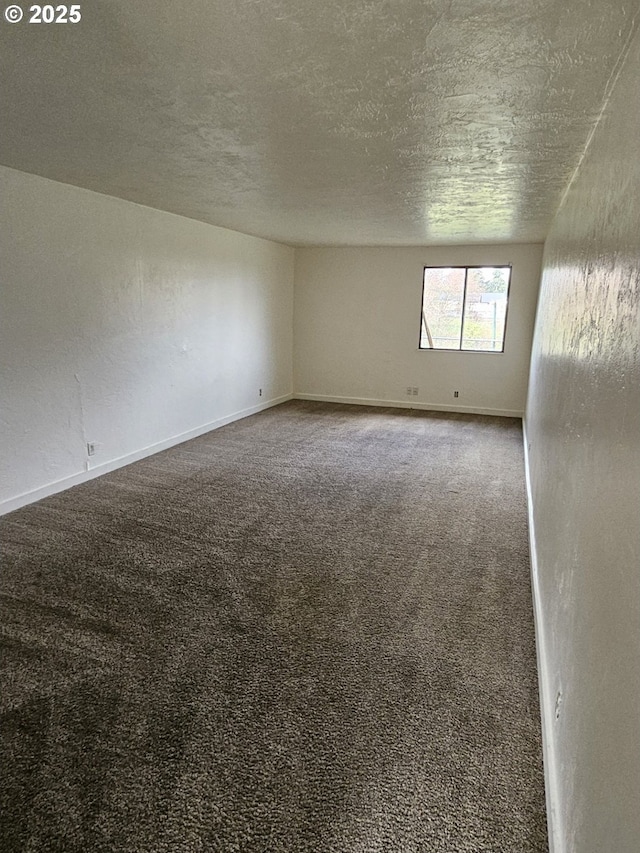 unfurnished room with a textured ceiling, carpet floors, and baseboards