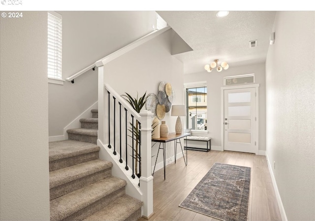 entrance foyer featuring visible vents, a textured ceiling, wood finished floors, stairway, and baseboards