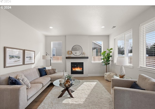 living room featuring visible vents, baseboards, wood finished floors, and a fireplace