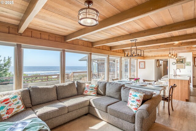 living area featuring wood ceiling, beam ceiling, a notable chandelier, light wood-style floors, and a water view