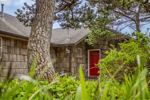 doorway to property with roof with shingles