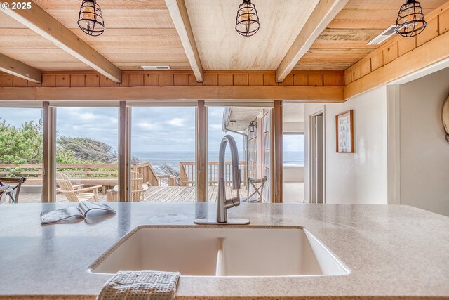 kitchen featuring wooden ceiling, beam ceiling, a wealth of natural light, and a sink
