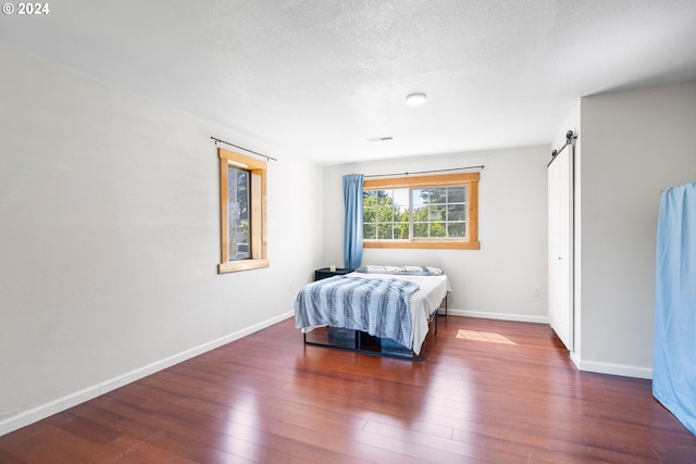108 SE 133rd Ave, Portland, OR 97233 - bedroom featuring visible vents, baseboards, a barn door, a textured ceiling, and hardwood / wood-style flooring