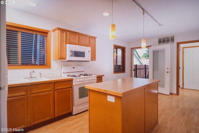 7942 N Hurst Ave, Portland, OR 97203 - kitchen with white appliances, light wood-style floors, a sink, a center island, and hanging light fixtures