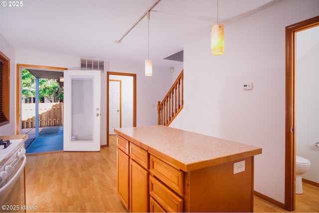 7942 N Hurst Ave, Portland, OR 97203 - kitchen featuring white range, light wood finished floors, light countertops, a center island, and pendant lighting
