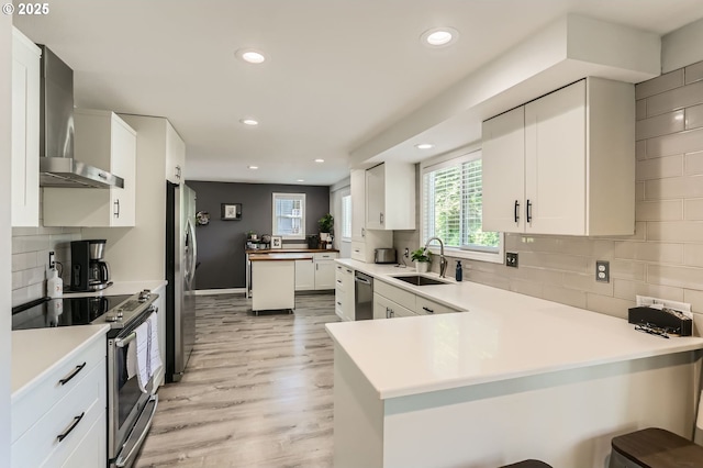 1736 Regency St, West Linn, OR 97068 - kitchen with stainless steel appliances, wall chimney exhaust hood, a peninsula, recessed lighting, and decorative backsplash