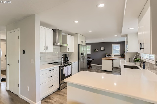 1736 Regency St, West Linn, OR 97068 - kitchen with wall chimney range hood, stainless steel appliances, wood finished floors, a peninsula, and decorative backsplash