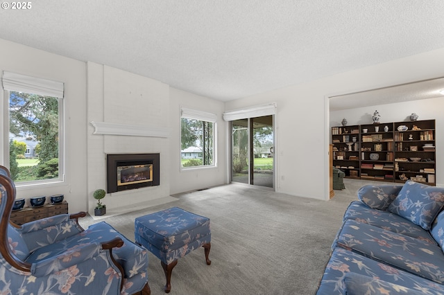 living area with a textured ceiling, a large fireplace, and carpet