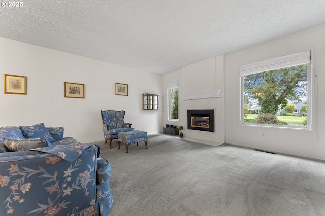 living area with carpet flooring, a fireplace, visible vents, and a textured ceiling