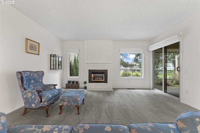 living area featuring a textured ceiling, carpet flooring, baseboards, and a large fireplace