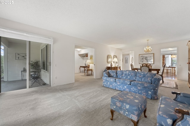 living area featuring carpet floors, a textured ceiling, and an inviting chandelier