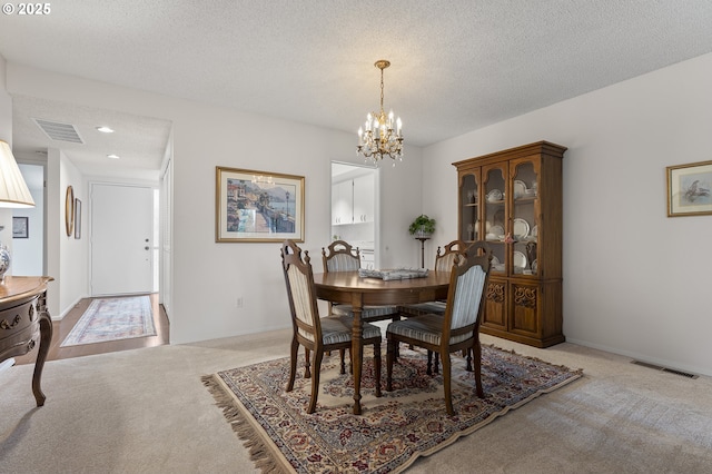 dining area featuring visible vents, light colored carpet, and an inviting chandelier