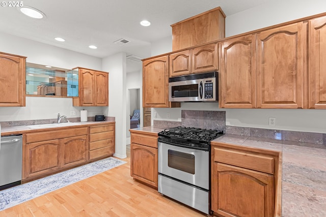 kitchen with stainless steel appliances, light hardwood / wood-style floors, and sink