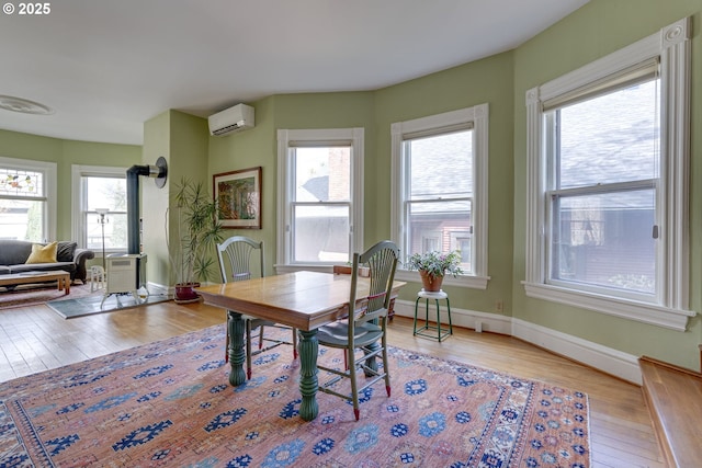 2122 NW Everett St, Portland, OR 97210 - dining space with an AC wall unit, wood-type flooring, and baseboards