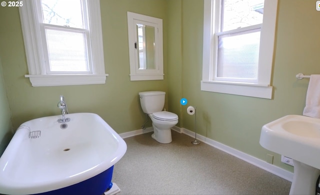 2122 NW Everett St, Portland, OR 97210 - bathroom featuring a freestanding bath, baseboards, and toilet