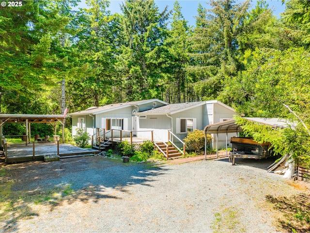 58897 Constance Dr, Bandon, OR 97411 - view of front of home with a detached carport, gravel driveway, a wooden deck, and board and batten siding