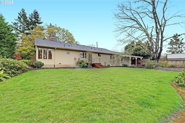 rear view of property featuring a chimney, fence, and a lawn