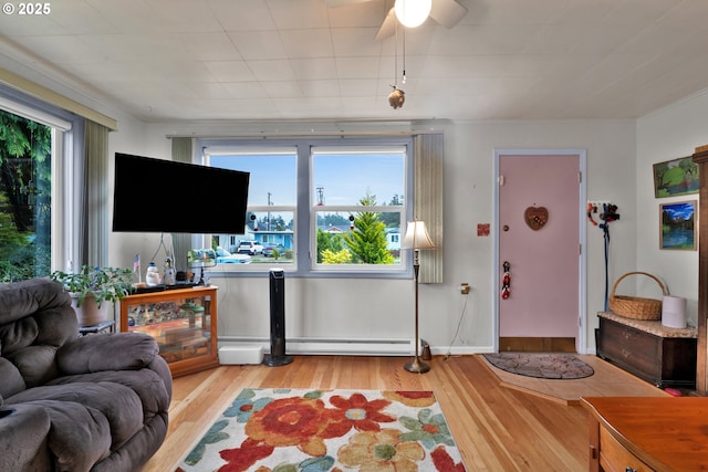 living area with baseboard heating, wood finished floors, and a ceiling fan