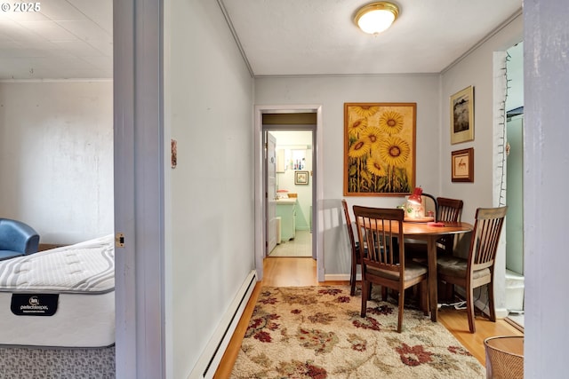 dining room featuring ornamental molding, baseboards, wood finished floors, and a baseboard radiator