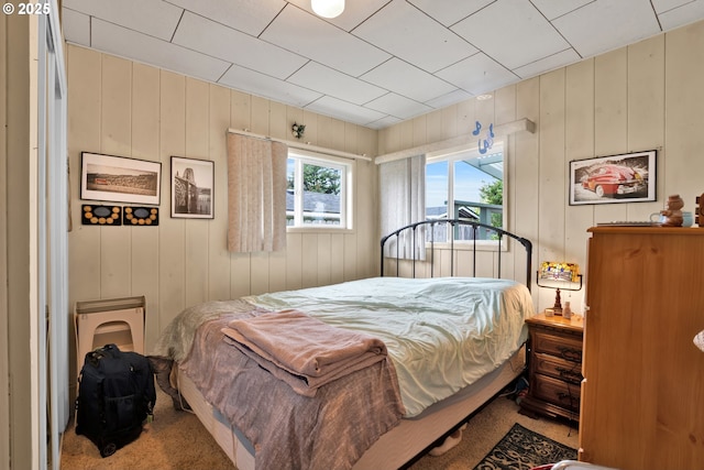 bedroom with wooden walls and carpet flooring