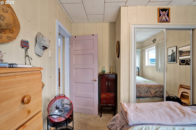 carpeted bedroom with wood walls