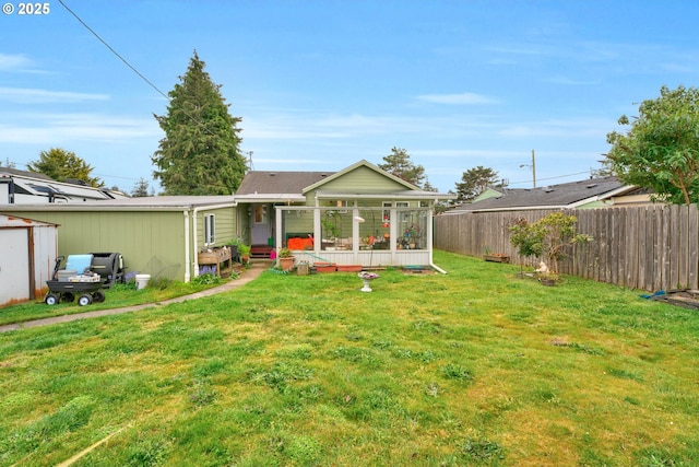 back of house featuring fence, a yard, and a sunroom