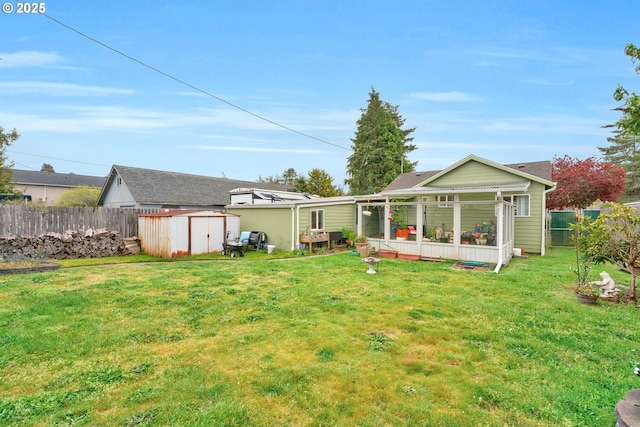 back of house featuring an outdoor structure, a shed, a lawn, and fence private yard
