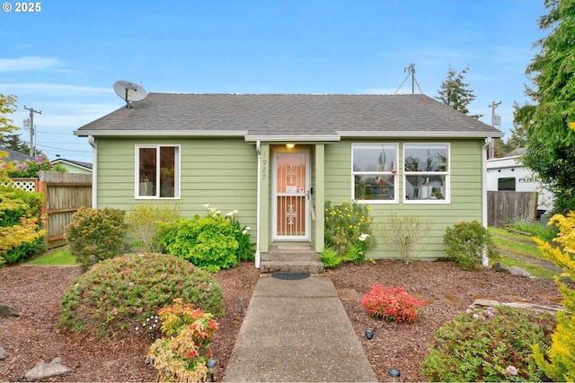 bungalow-style home with fence and roof with shingles