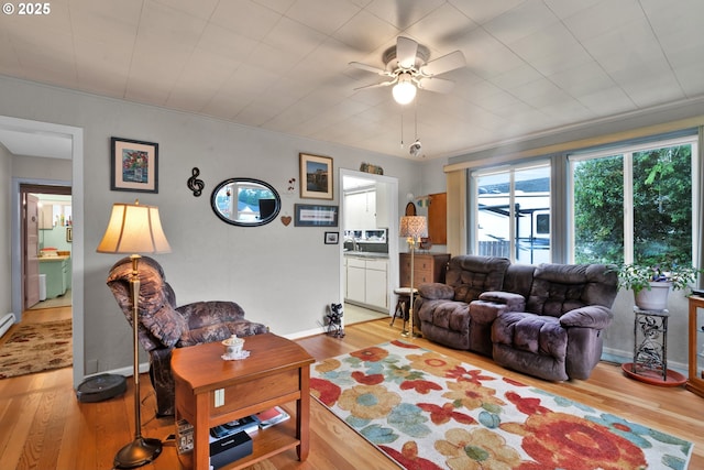 living room with wood finished floors, ceiling fan, and baseboards
