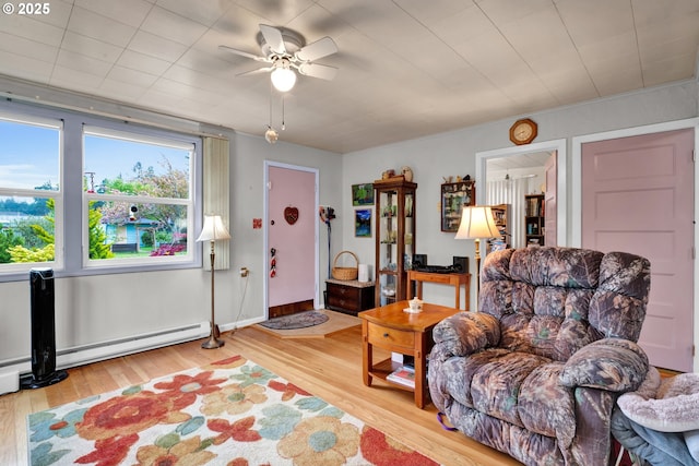 sitting room featuring wood finished floors, a ceiling fan, and a baseboard heating unit