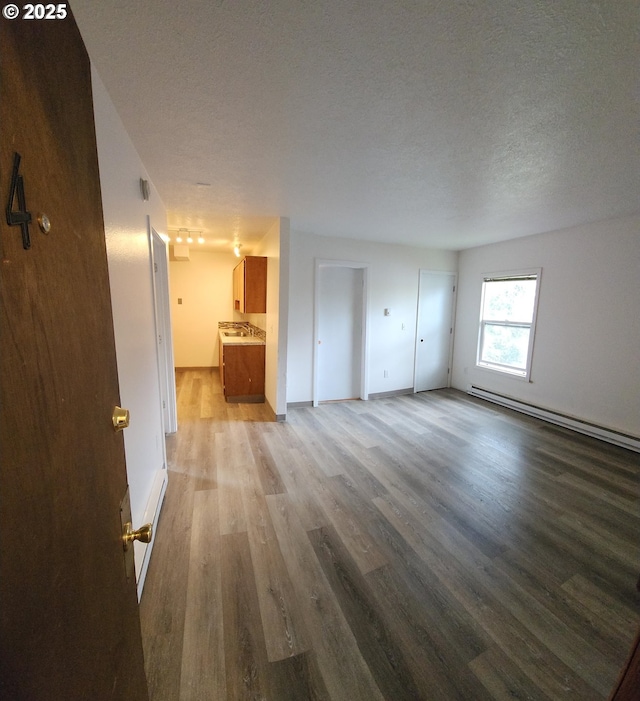 interior space featuring a baseboard radiator, connected bathroom, light hardwood / wood-style floors, and a textured ceiling