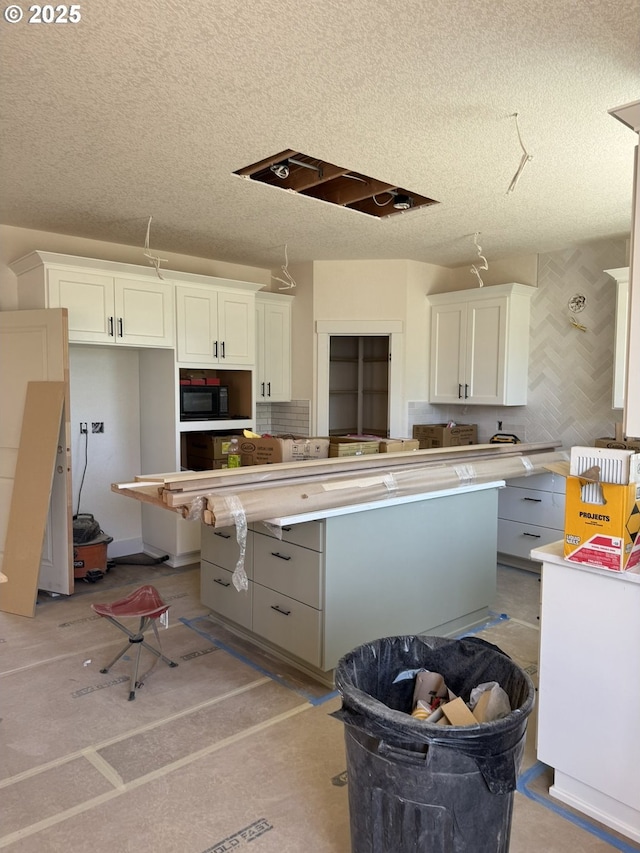 1900 S Holly St, Canby, OR 97013 - kitchen featuring black microwave, a textured ceiling, white cabinetry, a kitchen island, and light countertops