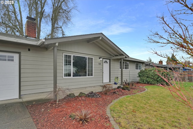 ranch-style house featuring an attached garage, a chimney, a front lawn, and fence