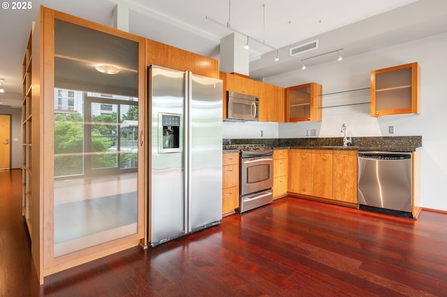 1221 SW 10th Ave Unit 311, Portland, OR 97205 - kitchen with appliances with stainless steel finishes, dark wood-style floors, glass insert cabinets, track lighting, and dark stone countertops