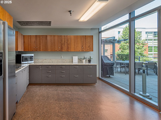 1221 SW 10th Ave Unit 311, Portland, OR 97205 - kitchen featuring appliances with stainless steel finishes, gray cabinets, plenty of natural light, and brown cabinetry