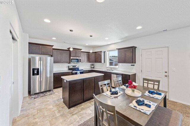 764 Seacrest Dr, Bandon, OR 97411 - kitchen featuring stainless steel appliances, dark brown cabinetry, a sink, a center island, and light countertops
