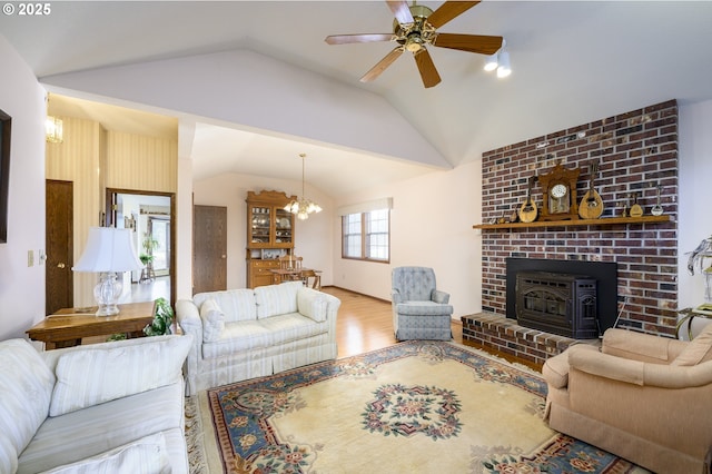 living room featuring ceiling fan with notable chandelier, vaulted ceiling, and wood-type flooring