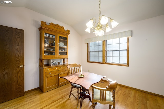 dining room featuring lofted ceiling, a chandelier, and light hardwood / wood-style floors