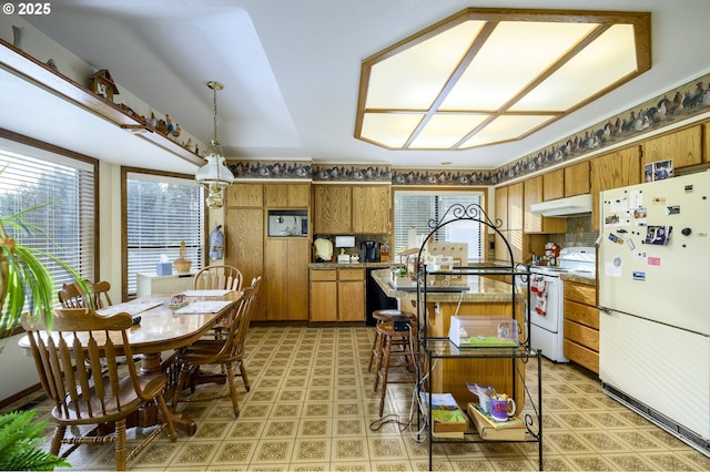 kitchen featuring hanging light fixtures, white appliances, and wood walls