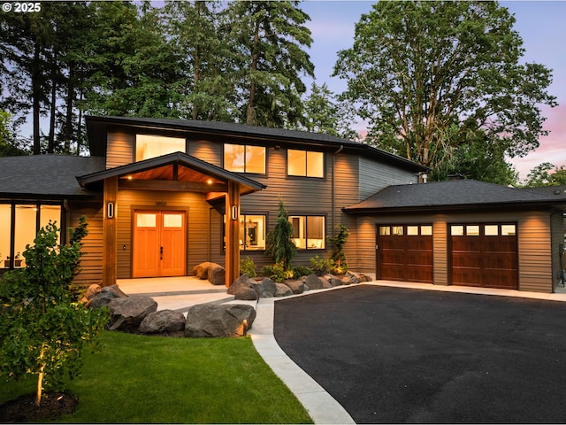 view of front of house featuring driveway, a garage, a shingled roof, and a front lawn