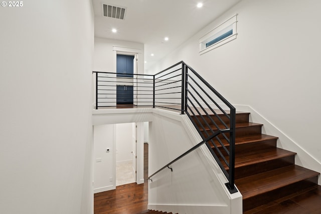 stairway featuring wood finished floors and recessed lighting