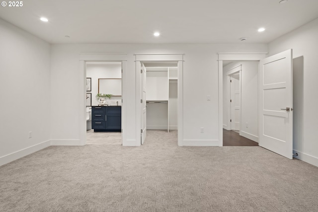 unfurnished bedroom featuring carpet flooring, recessed lighting, baseboards, and a walk in closet